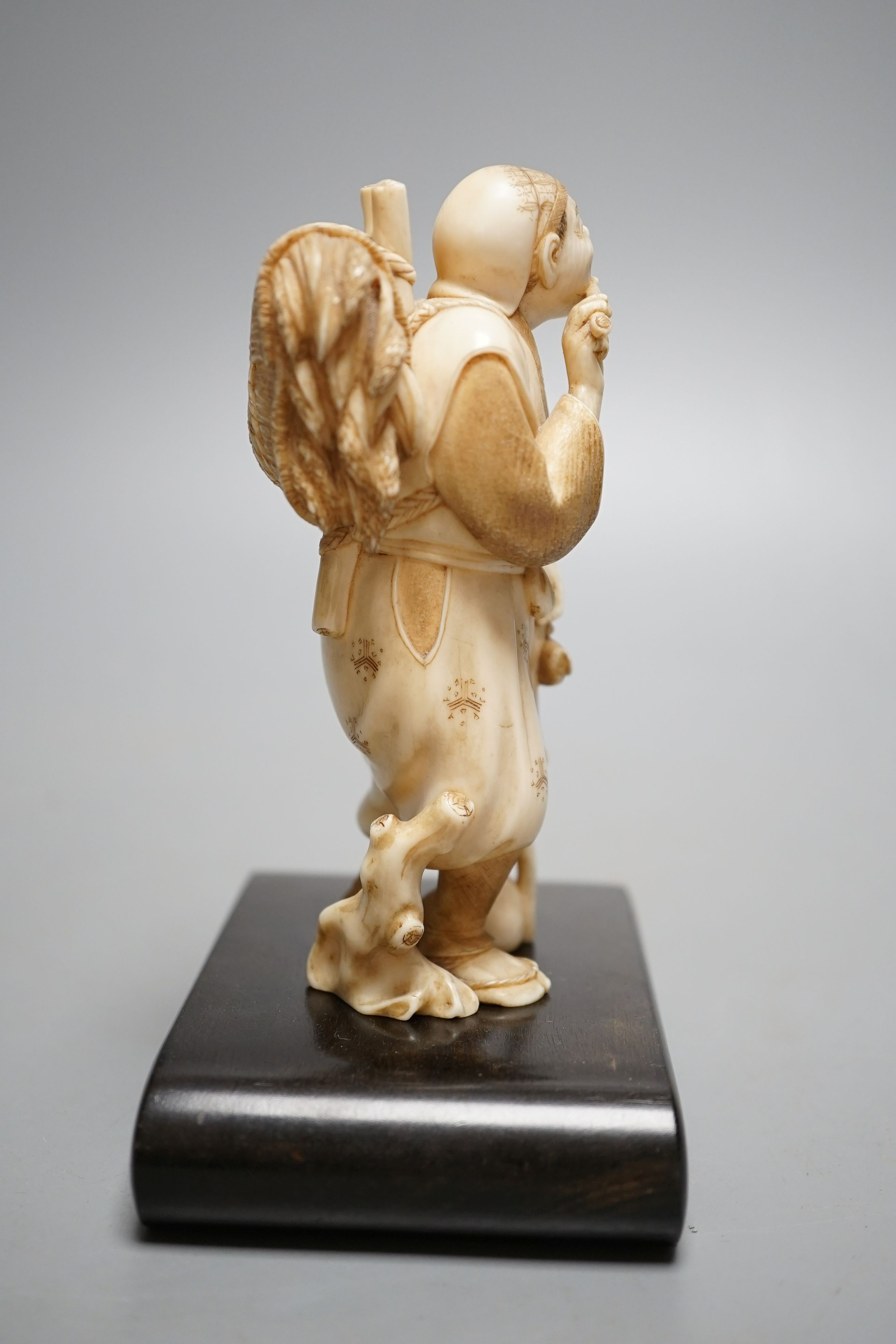 A Japanese ivory figure of a farmer smoking a pipe, Meiji period, signed - 12cm tall